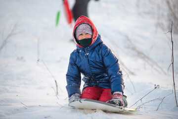 Happy child rides a sled down a snowy slope