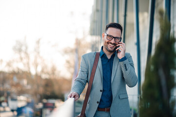 Businessman smiling while talking on phone outside office building