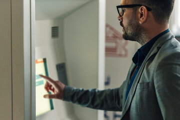 Businessman using interactive touchscreen kiosk in modern office building