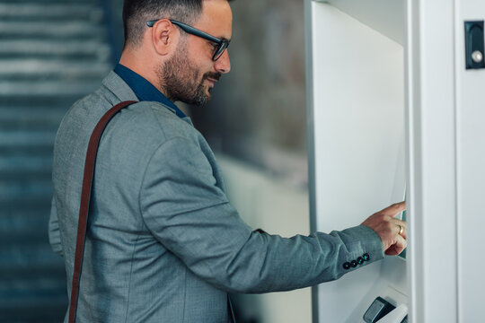 Businessman using touch screen of modern atm machine - Powered by Adobe