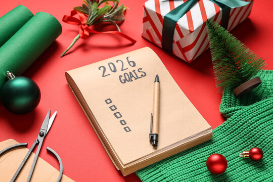 Notebook with empty to do list for 2026 year, sweater, gift and Christmas decor on red background - Powered by Adobe