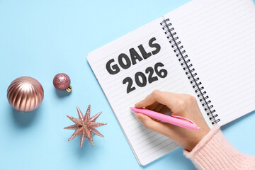 Woman making to do list for 2026 year on blue background