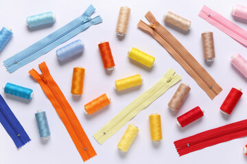 Colorful thread spools with zippers on white background