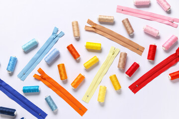 Colorful thread spools with zippers on white background