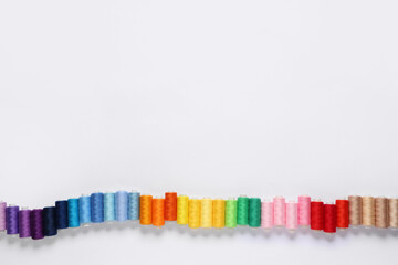 Row of colorful thread spools on white background