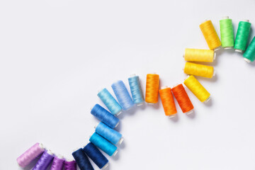 Row of colorful thread spools on white background
