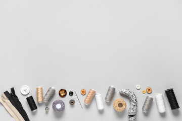 Set of thread spools with measuring tape and sewing supplies on grey background