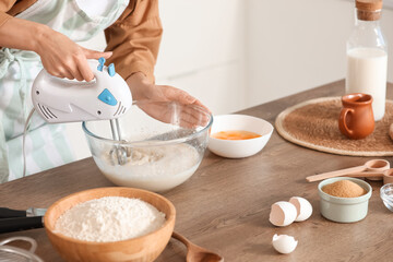 Young woman using mixer at table in kitchen, closeup