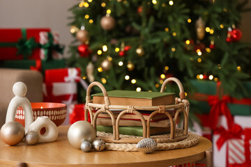 Tray with books and Christmas balls on table in living room