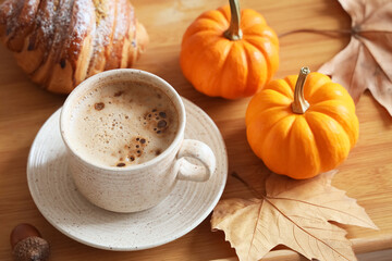 Cup of coffee with pumpkins, autumn leaves and croissant on tray, closeup