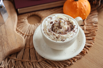 Cup of pumpkin latte on table, closeup