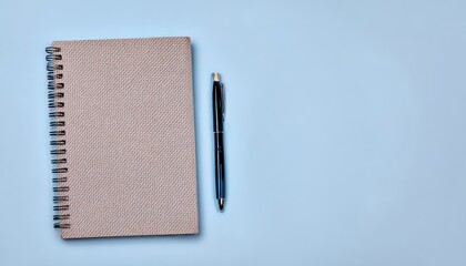 Spiral notebook and elegant pen creating a clean, organized workspace on a light blue pastel surface, perfect for notes and planning