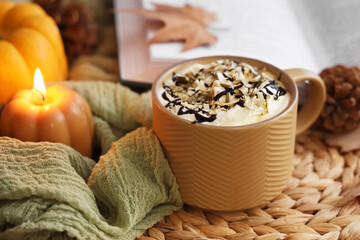 Cup of pumpkin coffee with burning candle on table, closeup