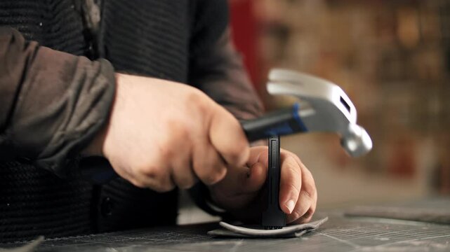 Craftsman hammering pricking chisel to make stitching holes in leather