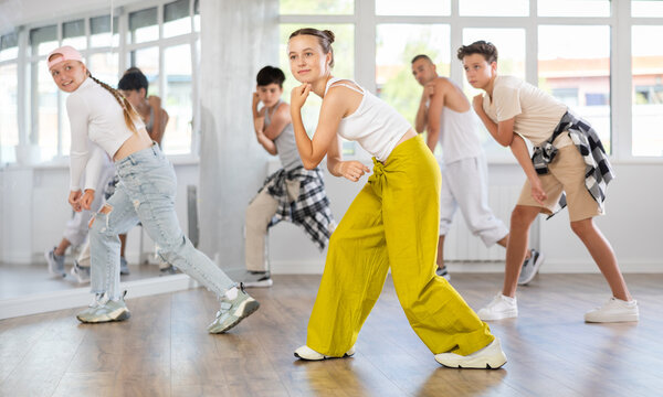 Teen girl dancing hip hop in group of teenagers in dance studio - Powered by Adobe