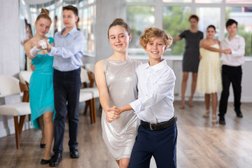 Obraz premium During rehearsal of reporting concert, adolescence boy and girl participants of dance workshop perform quickstep under guidance of female mentor