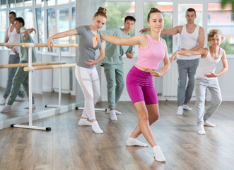 Naklejka premium In dance studio, teen girlie in group lesson with students rehearses, practices ballet dance, staging.