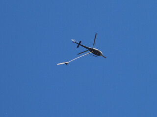 Helicopter flying with aerial pole saw. 