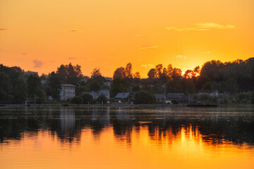 Evening summer landscape with houses on the lake. View of a small provincial Russian town. Beautiful sunset over Lake Valdayskoye. Valday town (Valdai), Novgorod region, Russia.