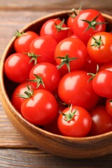 Fresh ripe tomatoes in bowl on wooden table, closeup