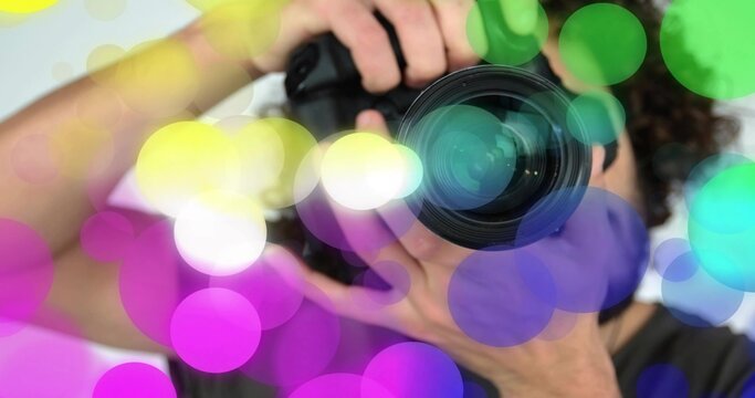 Holding DSLR camera photographer adjusting lens in studio, with lens cap and colorful bokeh overlay