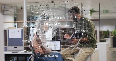 Collaborating colleagues tapping tablet and pointing at laptop screen in office, under data globe