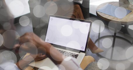 Colleagues collaborating in office lounge, with laptop showing crosshair markers plus smartphone