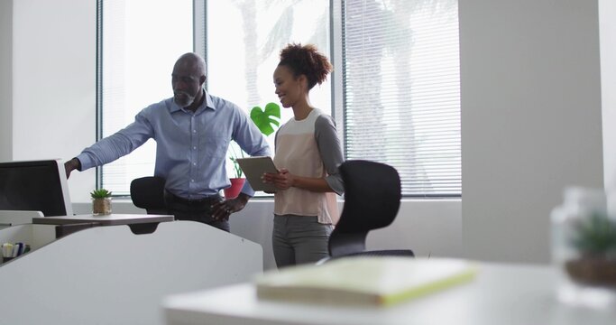 Colleagues in business attire collaborating at office desk with desktop monitor and tablet - Powered by Adobe