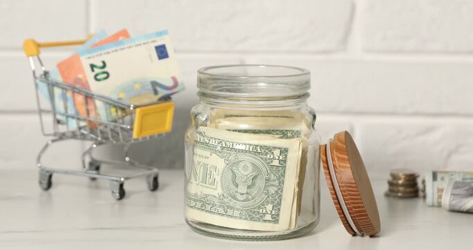 Woman putting money into jar at light table, closeup