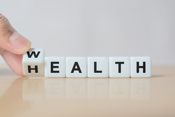 Hand flip dice with word wealth to health. Investment in life insurance and healthcare concept