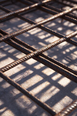 Iron Mesh Texture: An industrial close-up of iron mesh, casting intriguing shadows on a textured concrete surface. A showcase of architectural components and abstract textures.