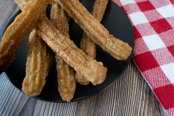 Top view of a plate of churros on a table accompanied by a checkered napkin, Mexican food