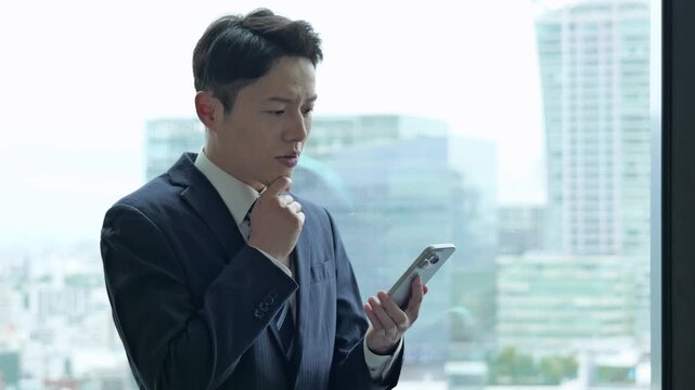 困った表情でスマートフォンを使うビジネスマン