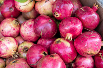 A vibrant display of fresh, ripe pomegranates at a market, showcasing their rich red hues and natural texture, perfect for healthy eating and harvest themes.