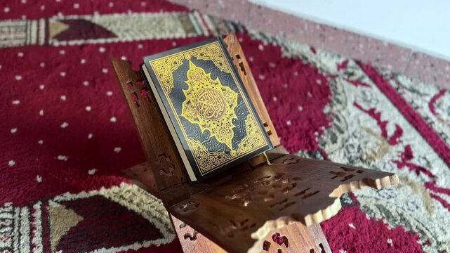 Close-up of the Holy Quran resting on a wooden rehal over a prayer rug. Symbol of Islam, spirituality, and devotion in a peaceful and sacred setting.