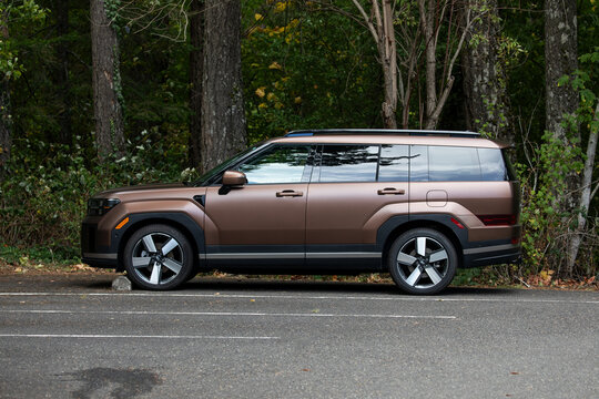Skamania, WA, USA - Sep 27, 2025 - Brown Hyundai Santa Fe hybrid SUV parked near forest area in Pacific Northwest environment, modern design family vehicle representing contemporary automotive style