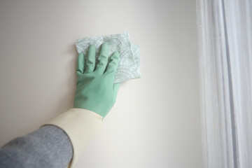 Cleaning a wall with gloves in a bright room