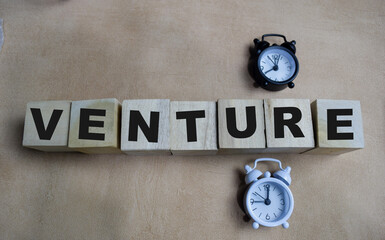 Venture on stacked wooden cubes on the table. Business and finance concept