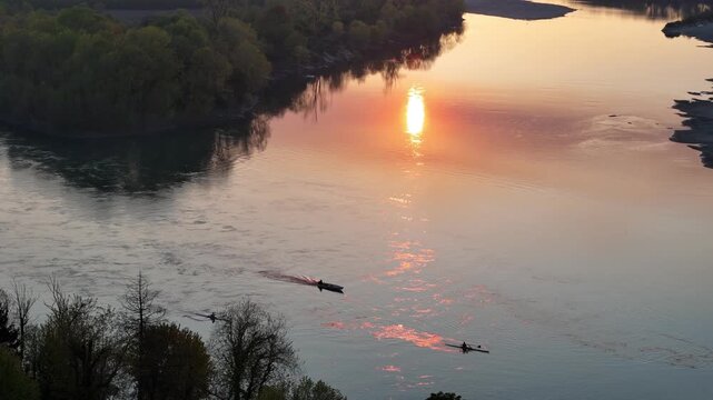 At sunset, rowers glide along the Po River at the Emilia Romagna&ndash;Lombardy border, their boats illuminated by golden reflections in the water, burning with fiery light that evokes flames