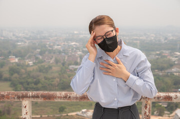 Asian woman having headache becaused of by Bad air pollution (PM2.5). PM2.5 levels meaning the air quality posed a health hazard.