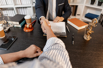 A professional lawyer in a suit shaking hands with a client in a legal office, symbolizing trust, successful agreement, and justice in legal consultation and professional law service.