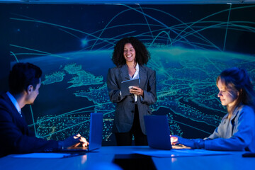 Diverse business team in a meeting, with a female leader presenting a global strategy on a large screen.