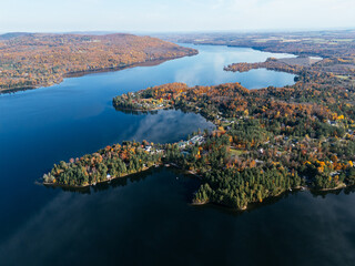 Drone aerial of a winding lakeside road with residential buildings and autumn forest in Canada. g.