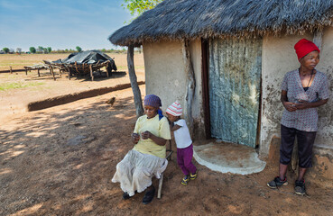 Loving African granny telling a story to her granddaughter in a village in Botswana