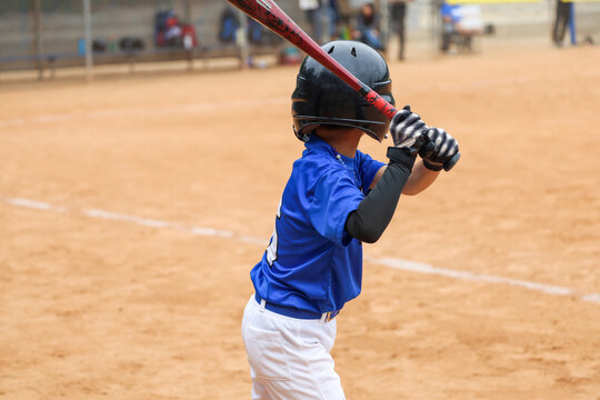 A 6 to 7 year old boy practicing batting while waiting for his turn to bat on the ballfield. Kids baseball game.