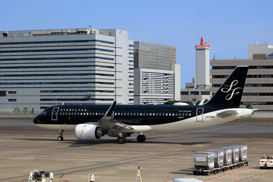 tokyo Japan - 2025 August 28: A Starflyer Airbus A320 aircraft taxis on the apron at Tokyo International Airport (Haneda, HND). Terminal buildings and a control tower are visible.