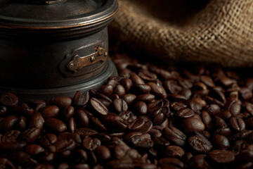 Coffee beans and a vintage grinder on a burlap surface