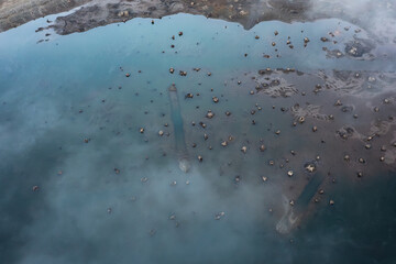 Aerial drone picture of Wynoochee Lake in Olympic National Forest, Washington State, USA, showing fog over turquoise water with visible submerged tree roots and stumps emerging from the surface	
