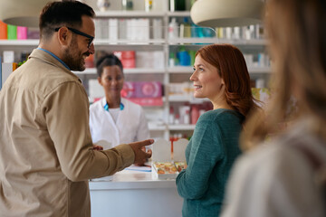 Happy couple talking while buying medicine in pharmacy.