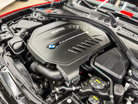 The M Performance Engine Cover With BMW Badge And Branding Of A B58 Turbocharged Engine In A BMW M140i Hatchback. BMW sport engine or motor under vehicle hood.